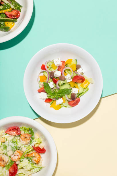 istock Greek salad in white plate hard shadows on blue and yellow 1335957731