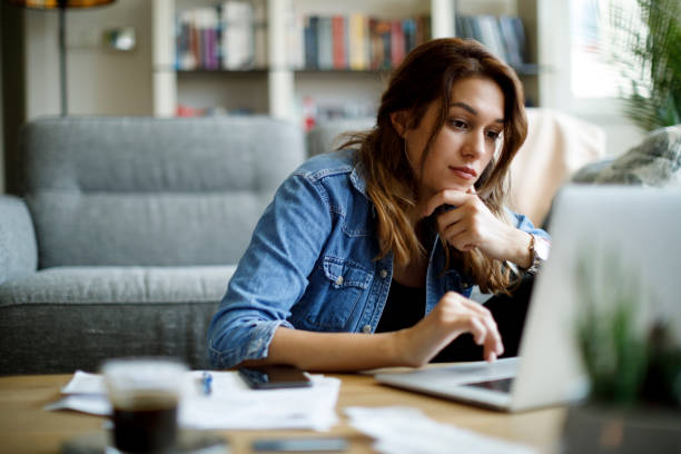istock Serious young woman using laptop at home 1335959002