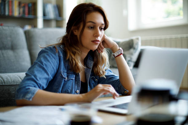 istock Serious young woman using laptop at home 1335959518