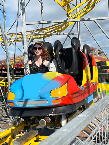 Stock photo showing an attractive young woman riding on a metal rollercoaster.