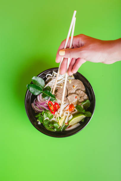 Fo Bo - Vietnamese Beef Soup on green woman hand with sticks