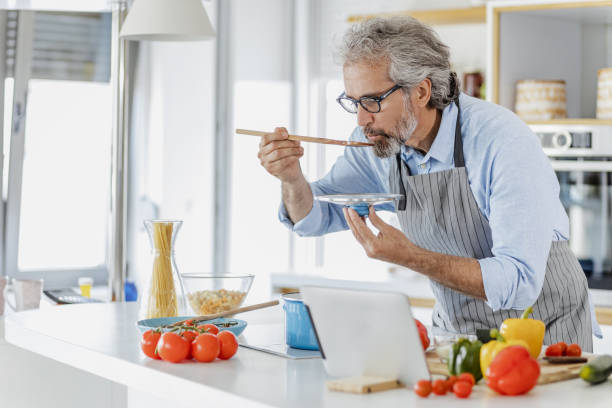 istock Senior man prepares a meal at home and tastes 1335964621