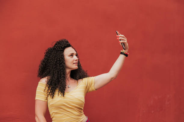 istock Beautiful smiling model with afro curls hairstyle makes selfie photos 1335964775