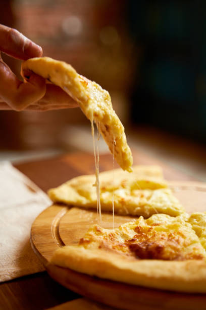 heiße khachapuri im imeretischen stil. schmelzkäse dehnen. unglaublich leckeres gericht - ajaria stock-fotos und bilder