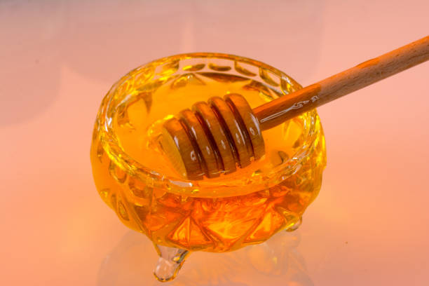 istock A pot of honey and a ladle, on a pink background as a packaging design element 1335968305