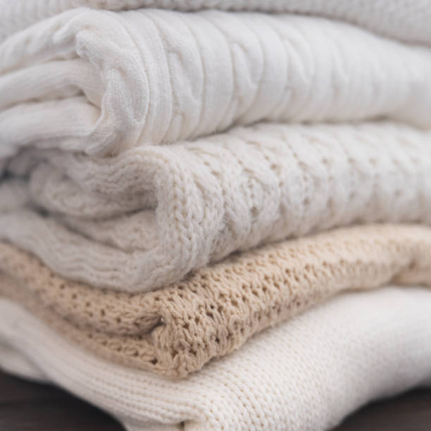 istock White and beige sweaters are stacked. Different knitted patterns. Autumn or winter background. 1335969961