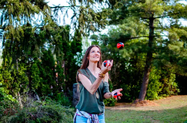 Young Woman juggling with small balls in green nature, practicing balance. Copy space