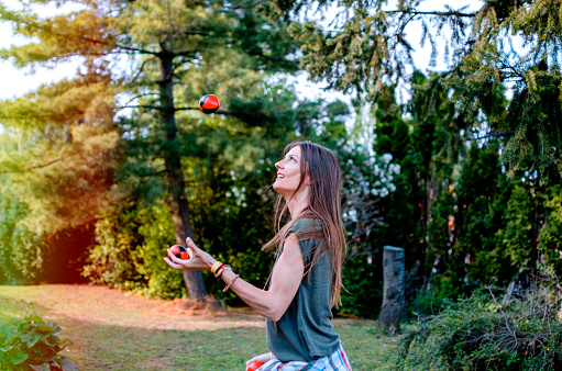 Young Woman juggling with small balls in green nature, practicing balance. Copy space