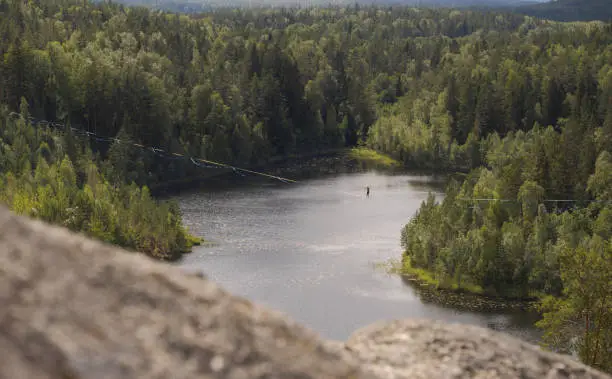 Highline over a lovely forest lake. Tightrope walker in action