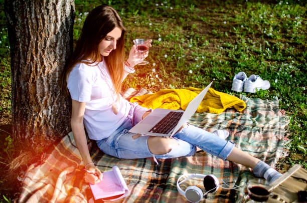 une étudiante utilisant un ordinateur portable à l’extérieur - women grass glasses e reader photos et images de collection