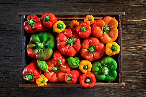 Table top view of a variation of multi colored bell pepper and chili peppers with copy space in a crate