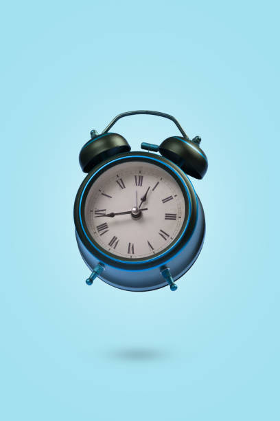 istock Minimal scene with an alarm clock floating in the air on a blue background 1335973717