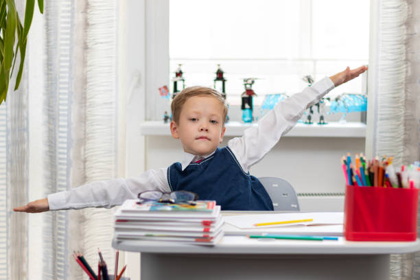 istock Cute boy first grader in school uniform at home during a break fooling around while sitting at his desk. Selective focus. Close-up 1335973734