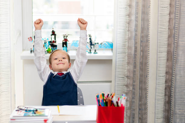 istock Cute boy first grader in school uniform at home during a break fooling around while sitting at his desk. Selective focus. Close-up 1335973788