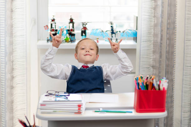 istock Cute boy first grader in school uniform at home during a break fooling around while sitting at his desk. Selective focus. Close-up 1335973795