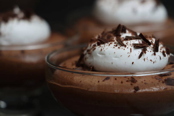 istock Full frame image of three glasses containing home-made chocolate mousse dessert topped with piped whipped cream and grated chocolate, black background, focus on foreground 1335975015