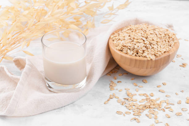 istock Glass with oat milk and a bowl with oat flake on white stone table 1335976128