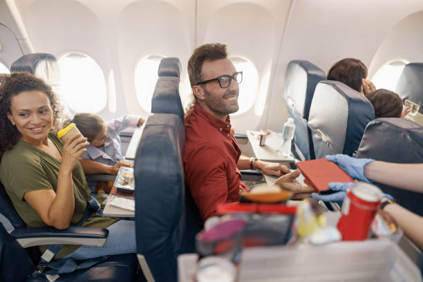istock Happy passengers smiling while female flight attendant serving lunch on board 1335981428