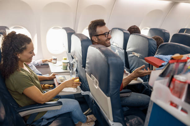 istock Cheerful passengers smiling, waiting for female flight attendant serving lunch on board 1335981429
