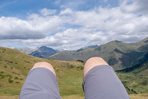 close up of the legs of a mountaineer lying on a peak with the mountains out of focus in the background, selective focus