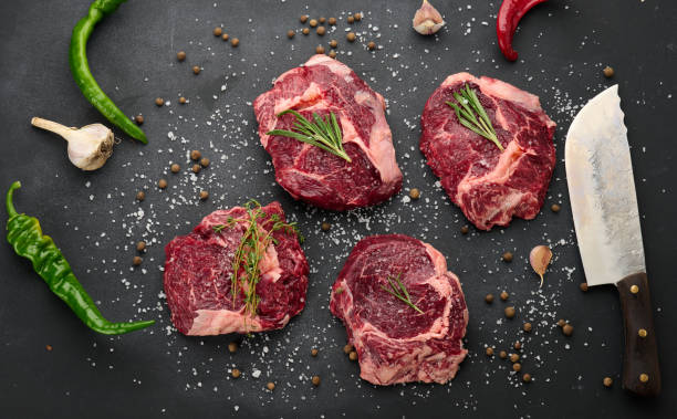 istock raw piece of beef ribeye with rosemary, thyme on a black table 1335984647