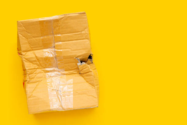 istock Damaged cardboard box with hole on yellow background. 1335990901
