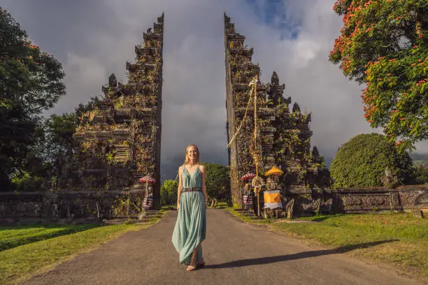 Photo of Tourist woman walking through Traditional Balinese Hindu gate Candi Bentar close to Bedugul, Bratan lake Bali island Indonesia. Vacation on Bali