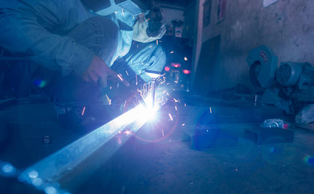 istock Welder welding metal with argon arc welding machine and has welding sparks. A man wears welding mask and protective gloves. Safety in industrial workplace. Welder working with safety. Steel industry. 1336008562