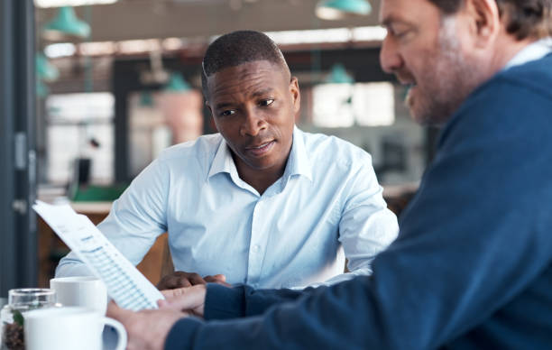 istock Shot of two businessmen going over paperwork in a modern office 1336009270