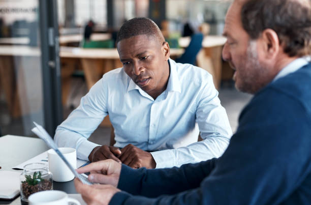 istock Shot of two businessmen going over paperwork in a modern office 1336009272