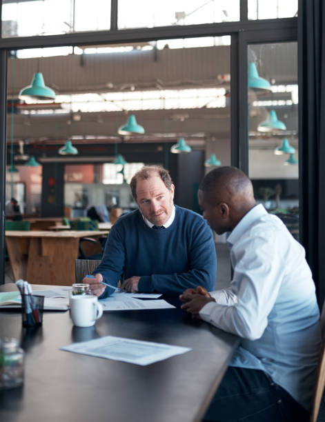 istock Shot of two businessmen going over paperwork in a modern office 1336009273