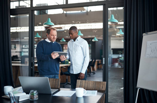 istock Shot of two businessmen using a digital tablet during a meeting in a modern office 1336009292