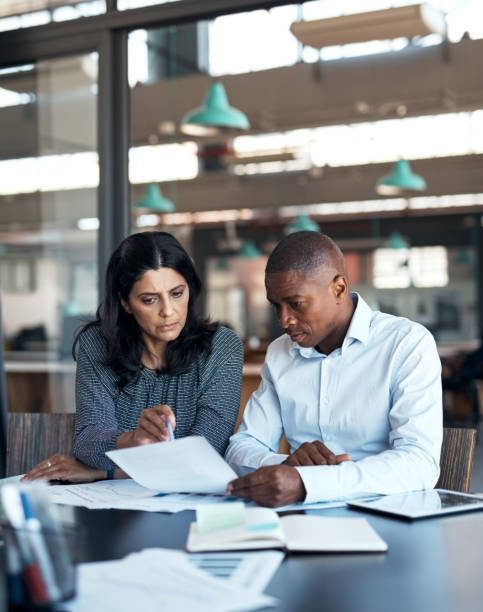 tiro de um empresário e empresária passando por cima da papelada em um escritório moderno - document strategy insurance business - fotografias e filmes do acervo