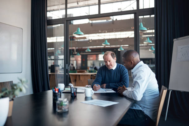 istock Shot of two businessmen going over paperwork in a modern office 1336009372