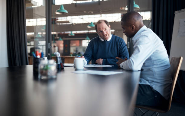 istock Shot of two businessmen going over paperwork in a modern office 1336009374