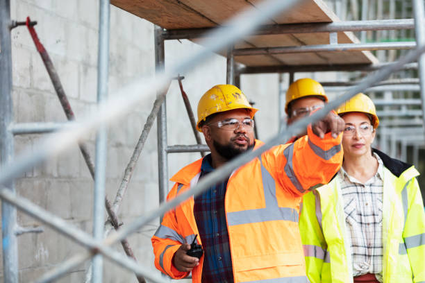 istock Woman, two men walk under scaffold at construction site 1336010540