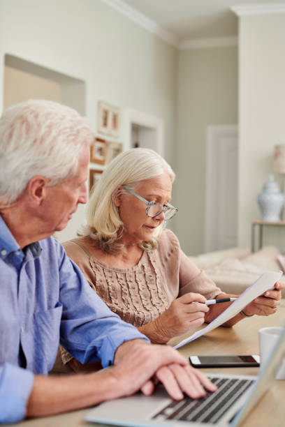 istock Shot of a senior couple using a laptop and going through paperwork at home 1336018849