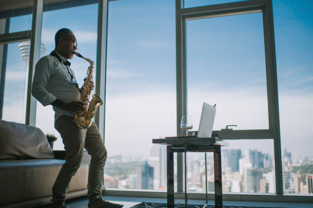istock Lifehack asian active senior man artist playing saxophone and showing it to his student using laptop in living room live streaming 1336021876
