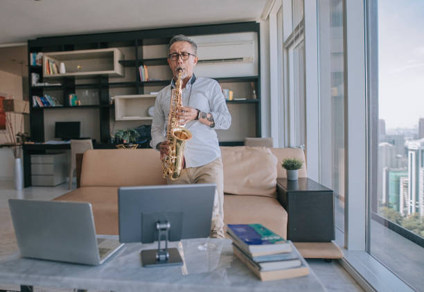 istock asian chinesse active senior man artist playing saxophone and showing it to his student using laptop at apartment living room in city live streaming 1336021918