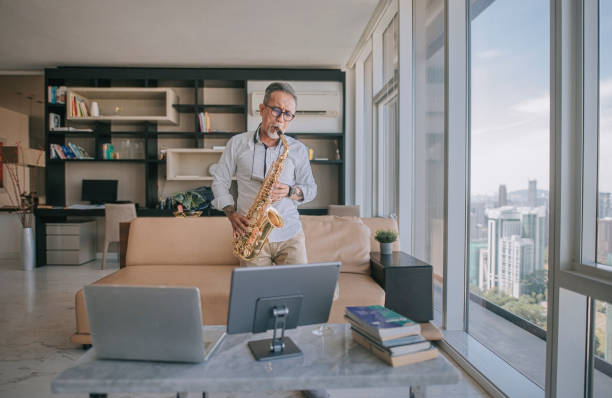 istock asian chinesse active senior man artist playing saxophone and showing it to his student using laptop at apartment living room in city live streaming 1336021940
