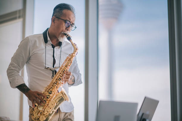 istock asian chinesse active senior man artist playing saxophone and showing it to his student using laptop at apartment living room in city live streaming 1336021951