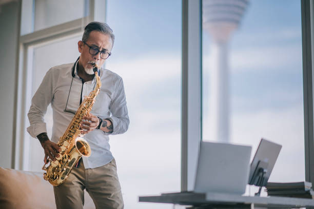 istock asian chinesse active senior man artist playing saxophone and showing it to his student using laptop at apartment living room in city live streaming 1336021961