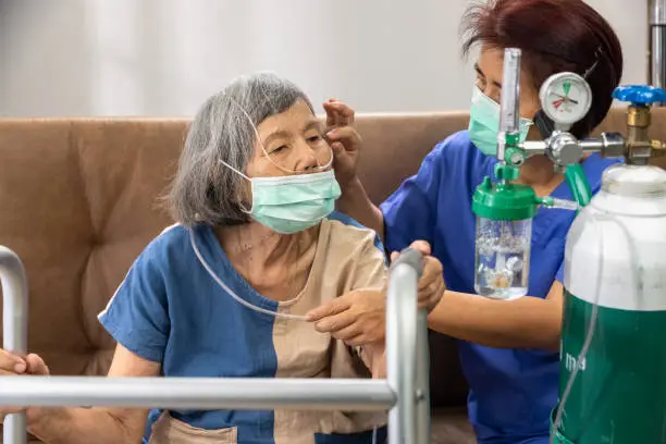 Photo of Elderly woman wearing oxygen nasal cannula at home.