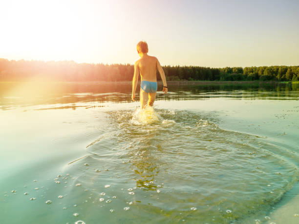 um garoto de 11 anos entra na água. o conceito de recreação, verão. - 10 11 years cheerful happiness fun - fotografias e filmes do acervo