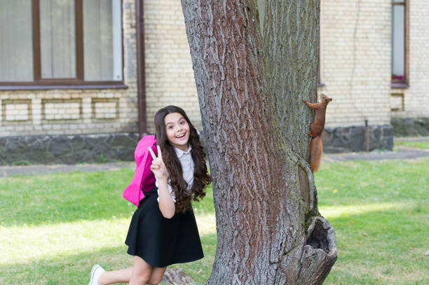istock Passionate about studying Zoology. Happy child show peace sign. Red squirrel climb tree trunk. Animal science. Zoology. Back to school. Natural science education. Becoming zoologist is in her future 1336039062