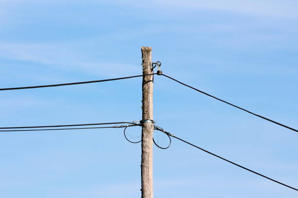 istock Cracked old wooden utility pole with thin black electrical wires connected with metal holders insulated with rubber 1336041243