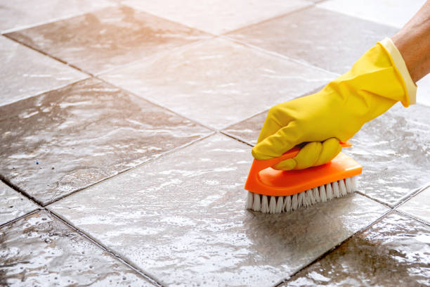 istock Hands wearing yellow rubber gloves are using a plastic floor scrubber to scrub the tile floor. 1336043004