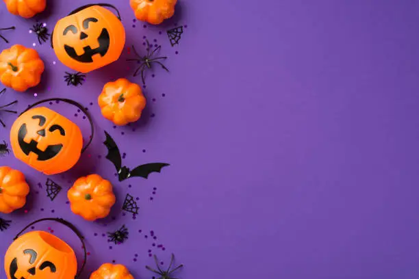 Photo of Top view photo of halloween decorations pumpkin baskets black sequins spiders web and bat silhouette on isolated violet background with empty space