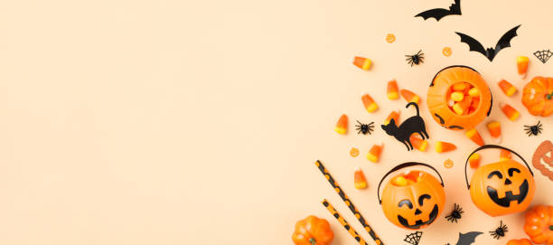 istock Top view photo of halloween decorations pumpkin baskets candy corn straws spiders web bats and black cat silhouettes on isolated beige background with copyspace 1336046276