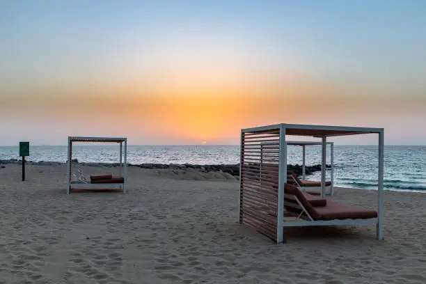 Empty sandy beach in Dubai with double sun beds, on new artificial Bluewaters Island, no people due to coronavirus COVID-19 pandemic, golden sunset.